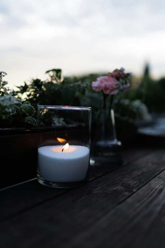Bougie allumée entourée de fleurs roses, symbole de recueillement pour le deuil périnatal