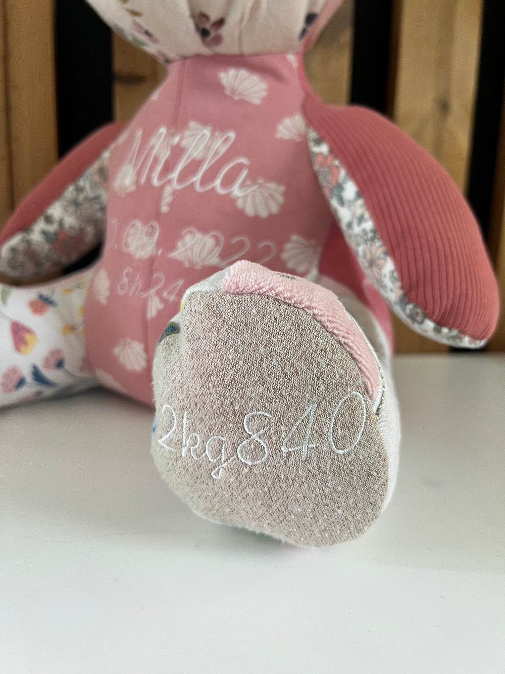 Détail de la patte de l'ourson brodée avec le poids de naissance de bébé pour l'option lestage