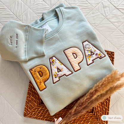Sweat souvenir personnalisé homme col rond vert d'eau brodé « PAPA » avec motifs hérissons, manche brodée prénom Lucie et date de naissance